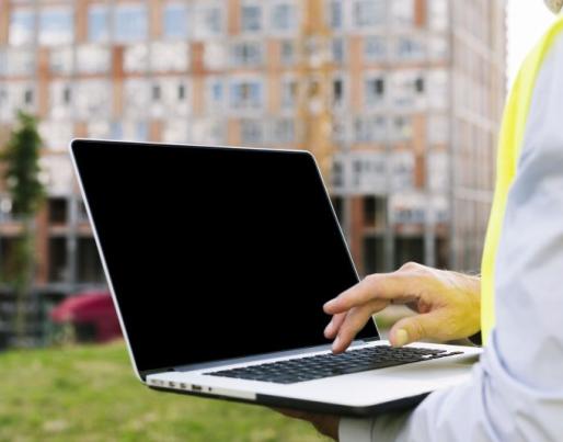 Man on construction site holding a laptop