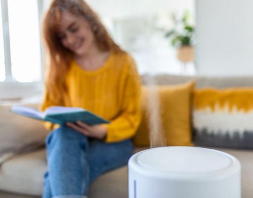 Air humidifier and woman reading a book on the sofa