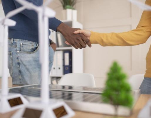 Two people shaking hands over renewable icons