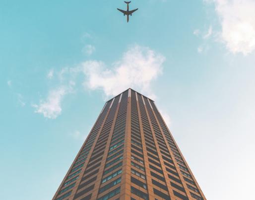 A plane flying over a tall building