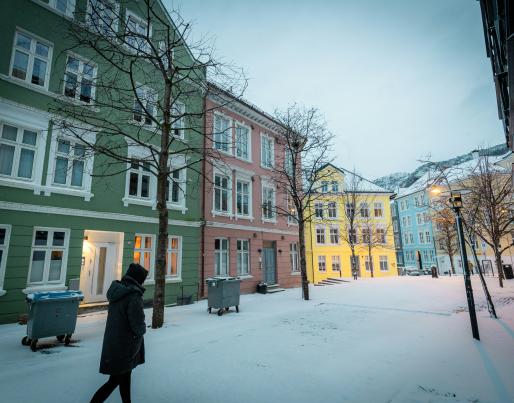 a person walking in the snow in front of a row of buildings