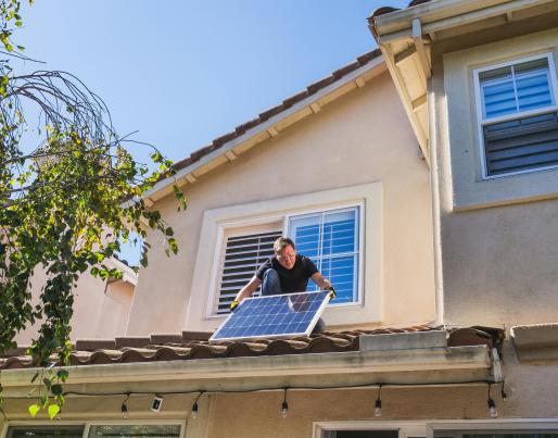 A Man Inspecting a Photovoltaic Panel on the Roof