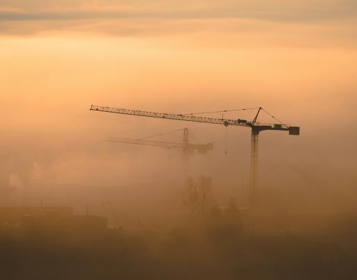 Construction cranes among the fog