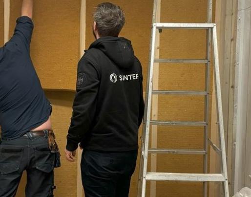 Two people renovating a wall with wooden plates
