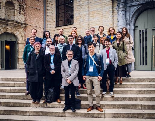 A group of people posing on the steps in front of a historic building. They are dressed formally, likely for an event or conference.