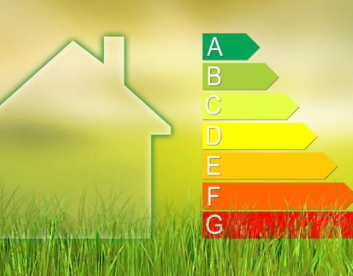 The image features the silhouette of a house on the left-hand side and an energy efficiency rating scale on the right. The scale comprises seven levels, labelled from A to G, with A in green and G in red, set against a yellow-green gradient background with grass at the bottom.
