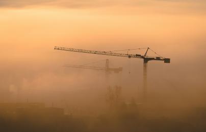 Construction cranes among the fog