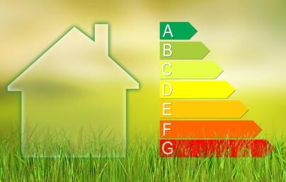 The image features the silhouette of a house on the left-hand side and an energy efficiency rating scale on the right. The scale comprises seven levels, labelled from A to G, with A in green and G in red, set against a yellow-green gradient background with grass at the bottom.