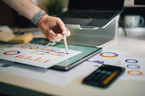 Desk with a tablet, papers with bar graphics and a calculator
