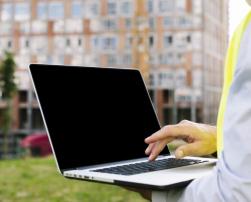Man on construction site holding a laptop