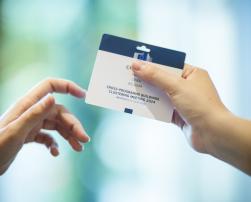 Two hands holding a credential of the event Cross-Programme Buildings Clustering Meeting 2024