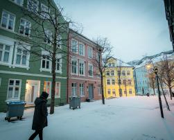 a person walking in the snow in front of a row of buildings