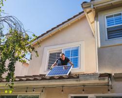 A Man Inspecting a Photovoltaic Panel on the Roof