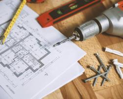 A drill and some screws on a blueprint on a table