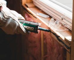 A men with a sealant near a window