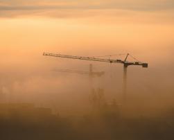 Construction cranes among the fog