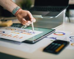 Desk with a tablet, papers with bar graphics and a calculator