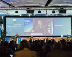 The image depicts a conference during European Sustainable Energy Week 2025, with Commissioner Dan Jørgensen speaking in front of a screen displaying the event’s theme.