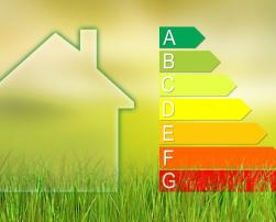 The image features the silhouette of a house on the left-hand side and an energy efficiency rating scale on the right. The scale comprises seven levels, labelled from A to G, with A in green and G in red, set against a yellow-green gradient background with grass at the bottom.
